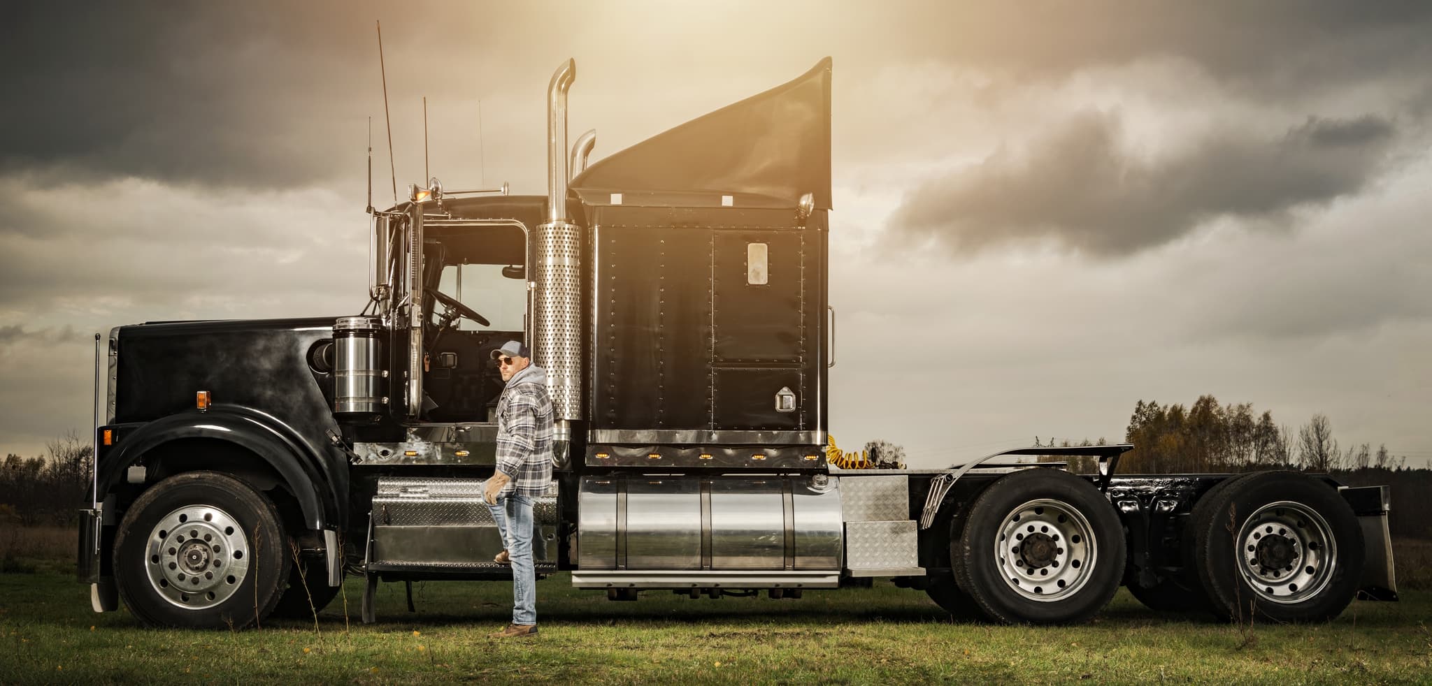 Owner-operator beside a semi-truck at golden hour